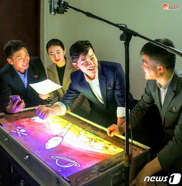 북한 첫 군사정찰위성 '만리경-1'호를 모래그림으로 창작하고 있는 만수대창작사 출판화창작단(사진=노동신문/뉴스1)