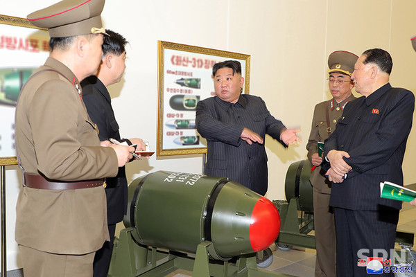 김정은 총비서가 새 핵탄두 '화산-31' 앞에서 핵무기병기화사업을 지도하는 모습. 벽에는 '화산-31'이 장착 가능한 무기들의 예시 그림들이 걸려있다.(사진=조선의 오늘)