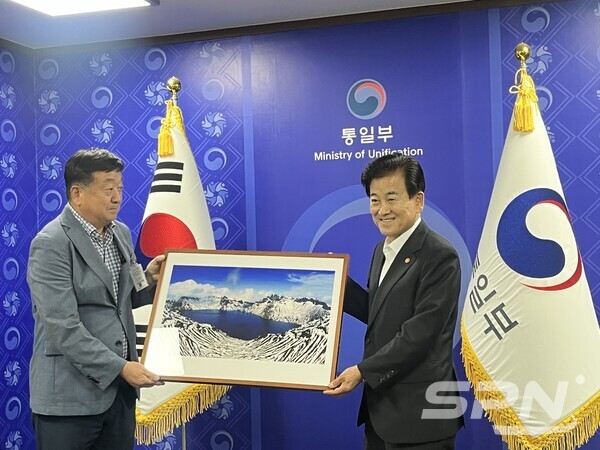 정동영 카지노 바카라부 장관(오른쪽)이 북측에서 촬영한 백두산 천지 사진을 김기창 한반도교역투자연합회 회장으로부터 전달 받고 있다. 백두산 사진은 이정수 작가가 촬영했다.(사진=SPN)